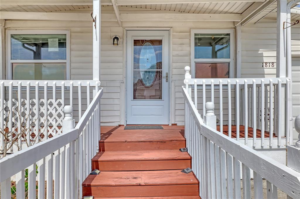 A wooden staircase leads to the front door of a house with white siding — 1818 BIG CYPRESS STREET NE, PALM BAY, FL