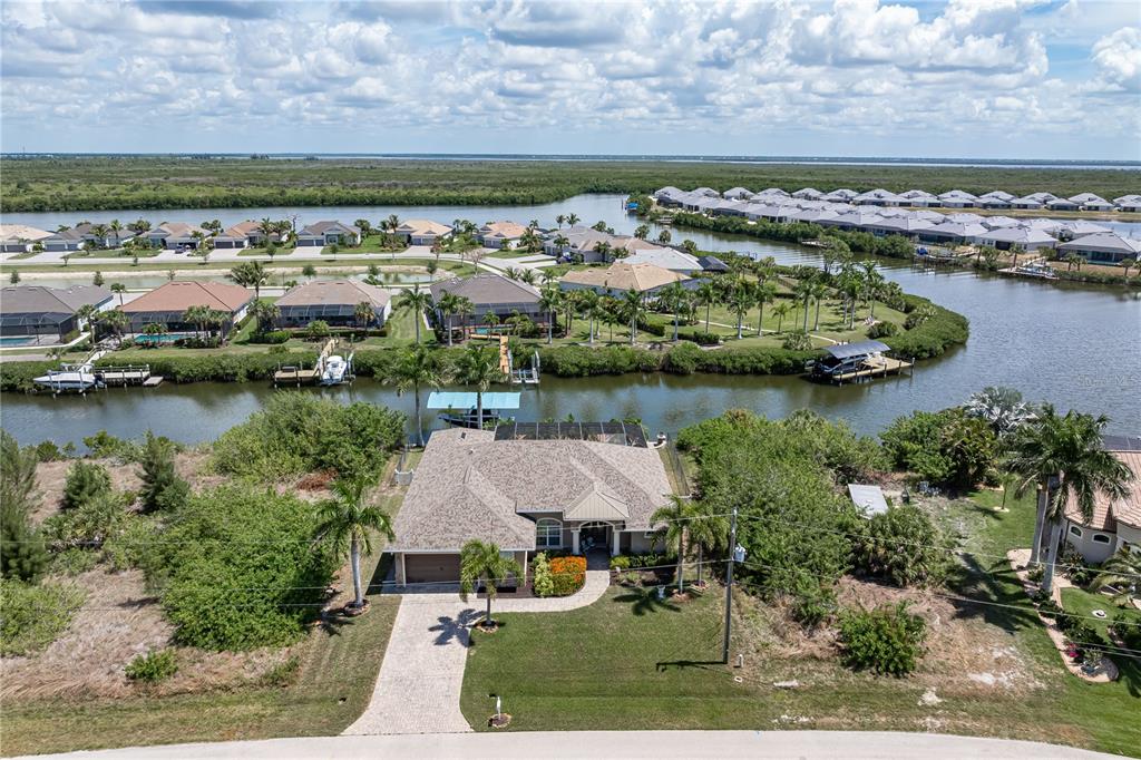 An aerial view shows a single-story house with a canal and other homes nearby — 15156 LEIPZIG CIRCLE, PORT CHARLOTTE, FL