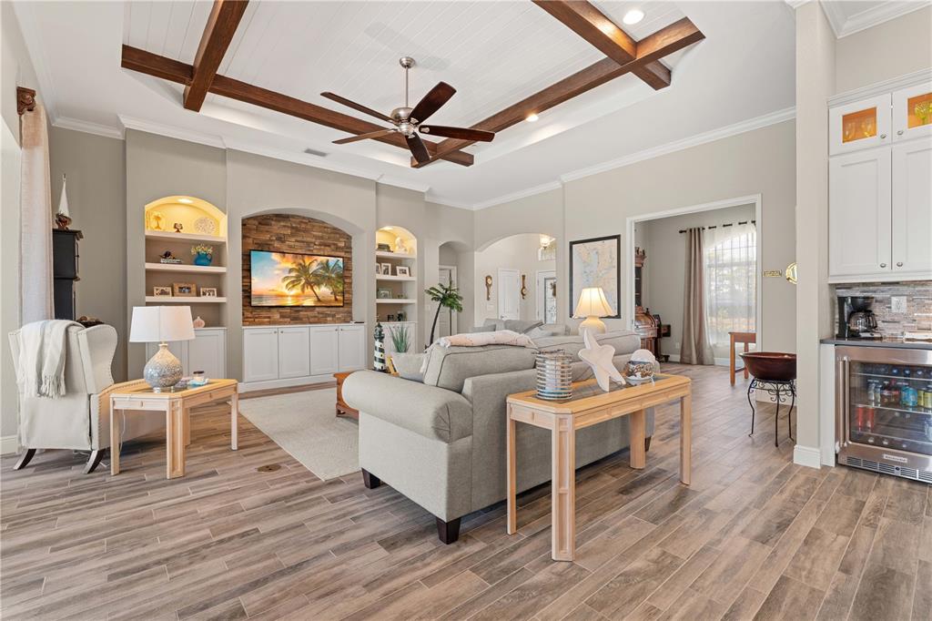 A living room features wood-look tile floors, a coffered ceiling, and a stone-accented media wall — 15156 LEIPZIG CIRCLE, PORT CHARLOTTE, FL