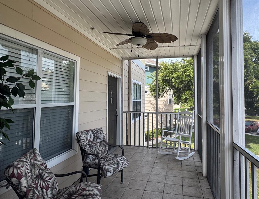 A screened-in balcony features tiled flooring, a ceiling fan, and three chairs — 4802 51ST STREET W UNIT 510, BRADENTON, FL