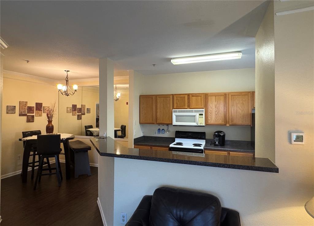 A kitchen with wooden cabinets and a breakfast bar overlooks a dining area with mirrors — 4802 51ST STREET W UNIT 510, BRADENTON, FL