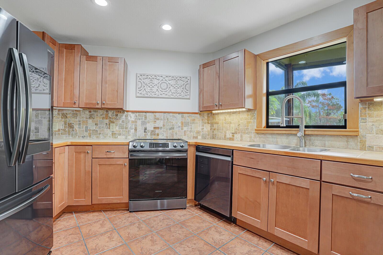 A kitchen features wood cabinets, stainless steel appliances, a tiled backsplash, and terracotta floor tiles — 9752 SE Highborne Way, Hobe Sound FL 33455, HOBE SOUND, FL