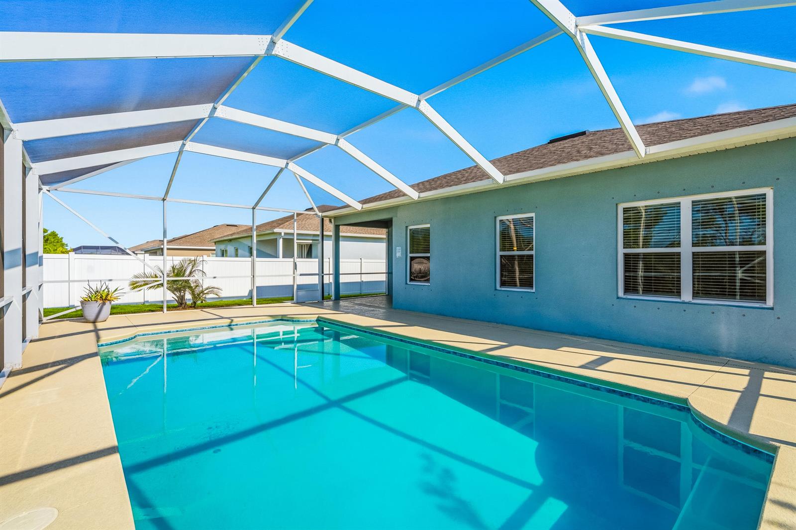 A swimming pool with a screened enclosure sits beside a blue house with white trim — 4213 Keeson Circle, Vero Beach FL 32967, VERO BEACH, FL