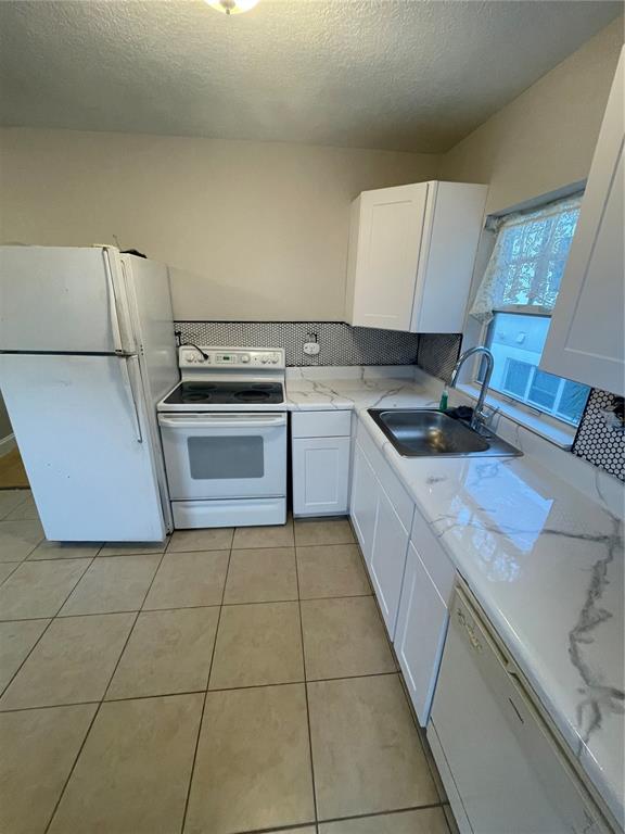 A kitchen features white cabinets, a white stove, a refrigerator, and marble-patterned countertops — 727 1/2 EDGEWATER DRIVE, ORLANDO, FL