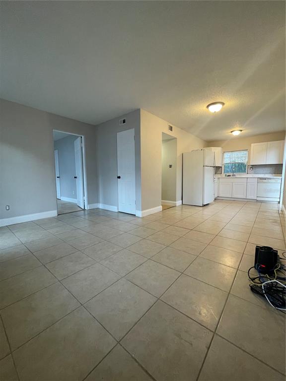 An open-concept kitchen and living area features light-colored tile flooring and white cabinetry — 727 1/2 EDGEWATER DRIVE, ORLANDO, FL