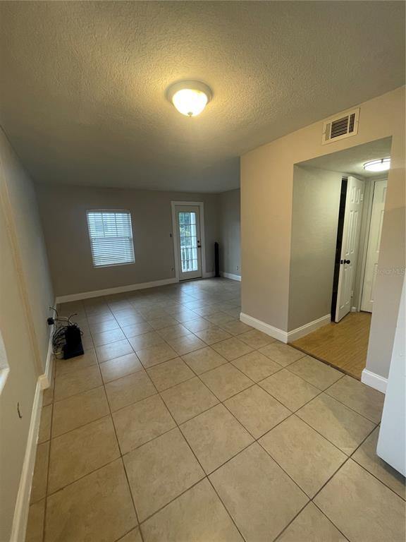 A room with beige tile flooring, a ceiling light, and a door leading outside — 727 1/2 EDGEWATER DRIVE, ORLANDO, FL