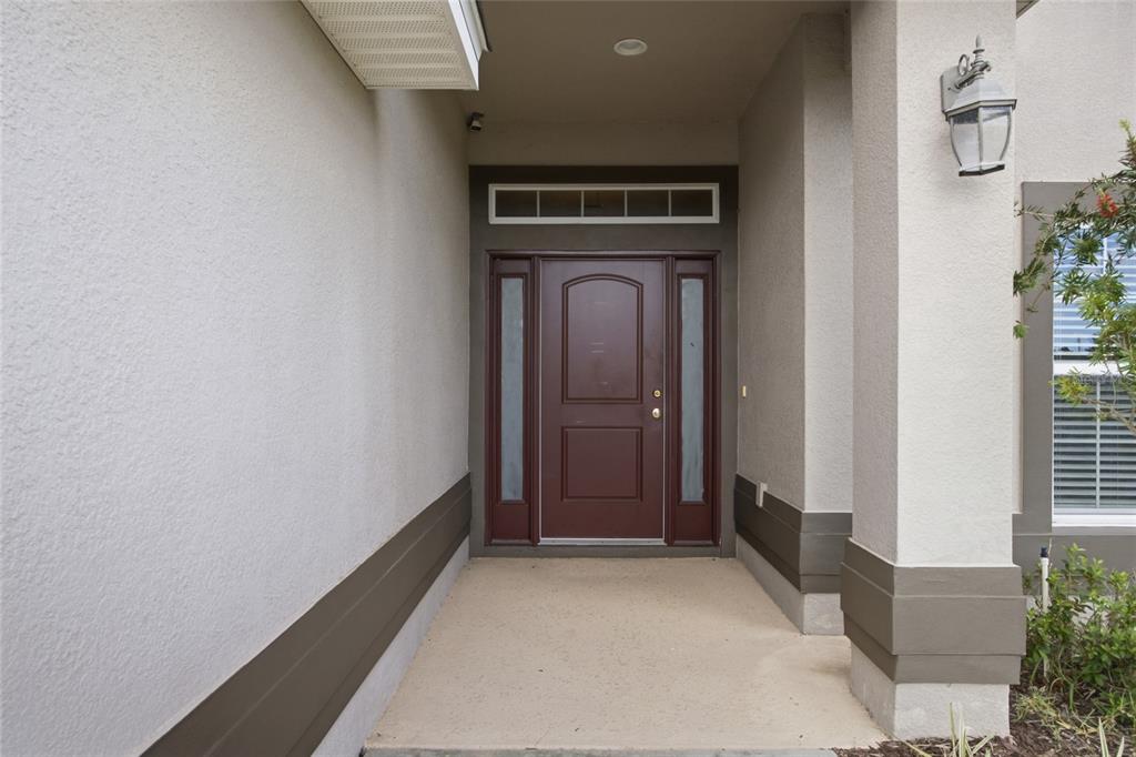 A covered entryway features a dark red front door with sidelights and a transom window — 3 DIAMOND COVE COURT, OCALA, FL