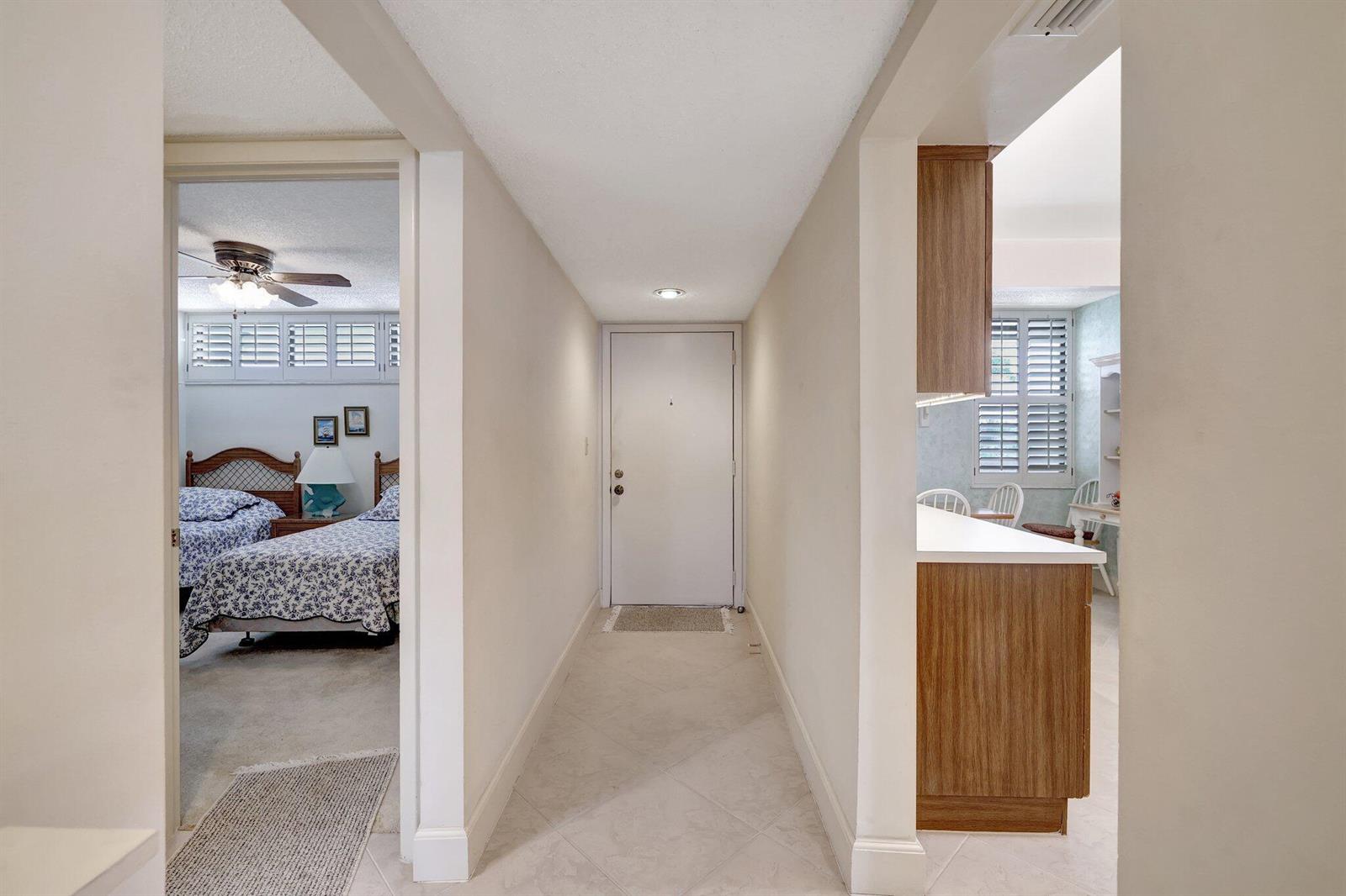 A hallway with tile flooring leads to a white front door, flanked by two rooms — 1950 SW Palm City Road # 304, Stuart FL 34994, STUART, FL