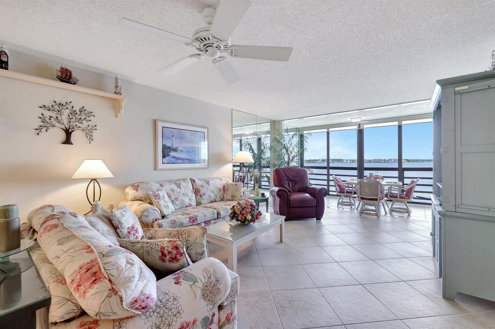 A living room with floral sofas, a ceiling fan, and a view of the water — 1950 SW Palm City Road # 304, Stuart FL 34994, STUART, FL