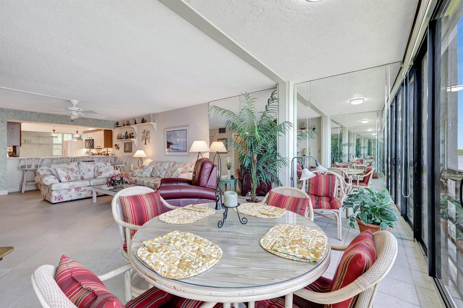 A dining area with a glass-topped table sits in front of a living room space — 1950 SW Palm City Road # 304, Stuart FL 34994, STUART, FL