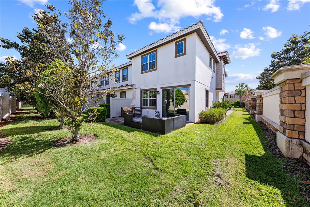 The exterior of a two-story townhouse features a small patio with furniture and a lawn — 14100 TARVIN STREET, ORLANDO, FL