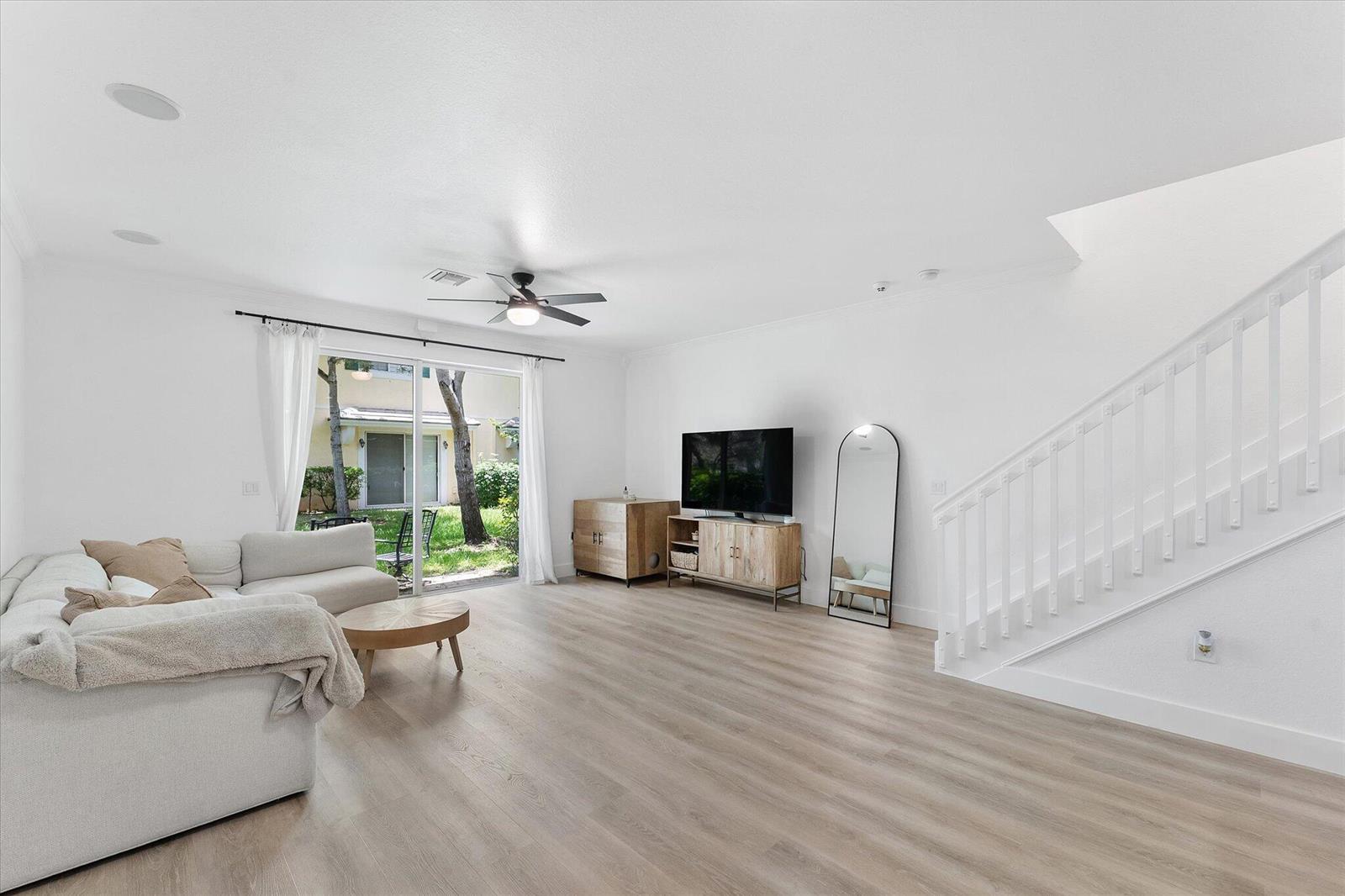 A living room features light wood flooring, a white sectional sofa, and a staircase — 7783 Deercreek Court, Davie FL 33328, DAVIE, FL
