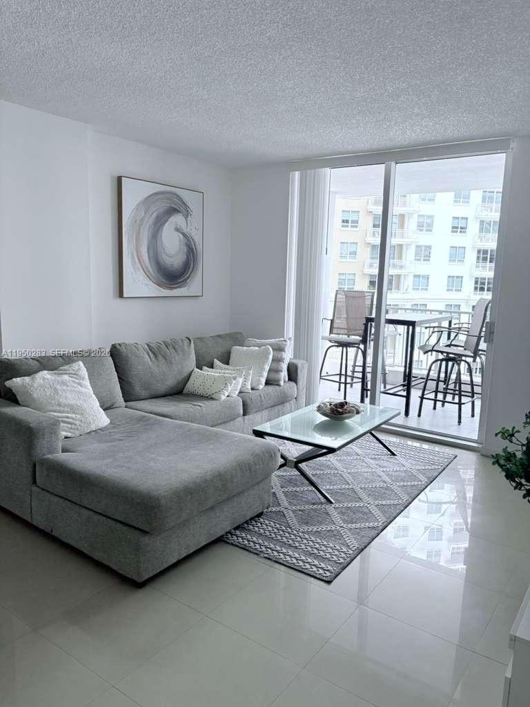 A living room features a gray sectional sofa, a glass coffee table, and a balcony — 701 Brickell Key Blvd # 1105, Miami FL 33131, MIAMI, FL