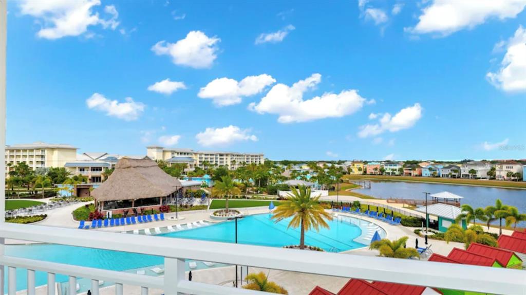 A high-angle view shows a resort swimming pool, a thatched-roof building, and a lake — 3151 SUNSET WALK DRIVE UNIT 411, KISSIMMEE, FL