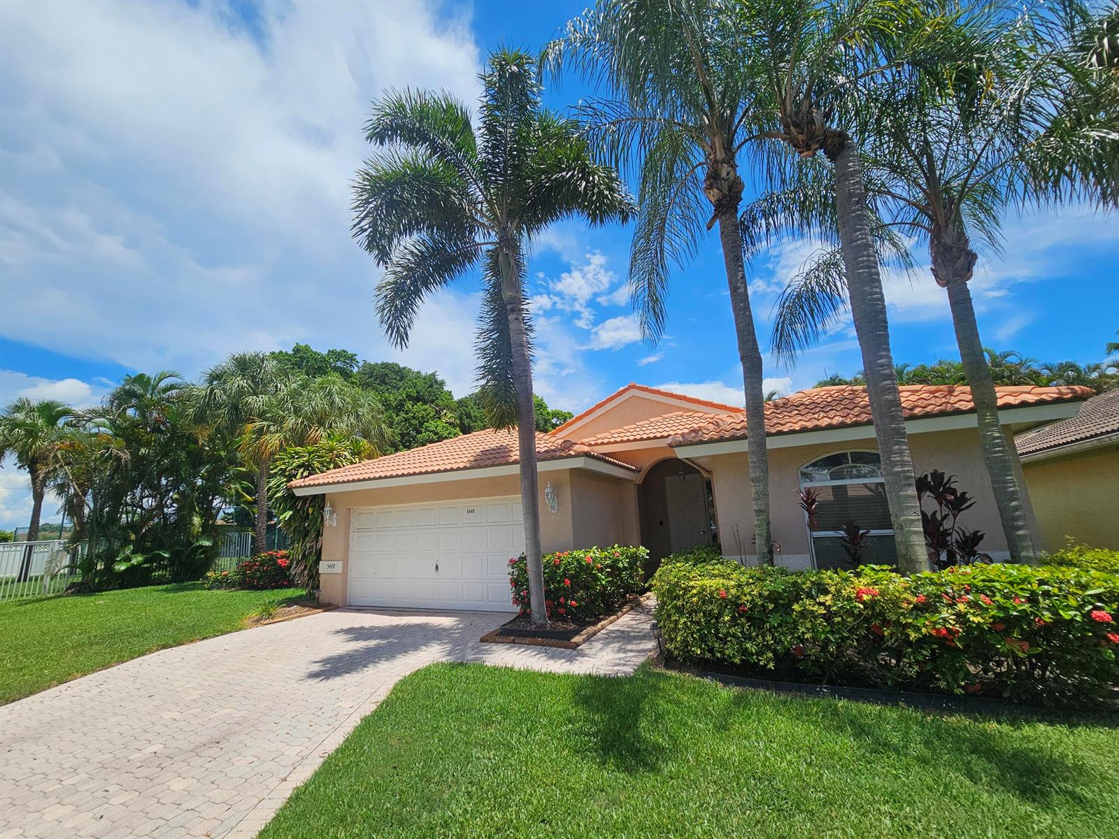 A single-story house with a tiled roof, white garage door, and palm trees in the yard — 5449 Grande Palm Circle, Delray Beach FL 33484, DELRAY BEACH, FL