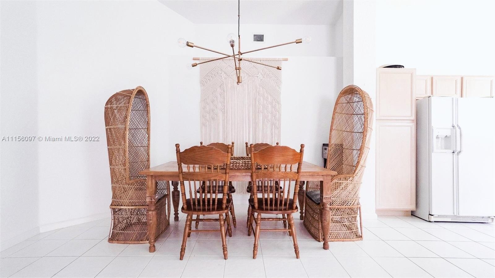 A dining room features a wooden table, spindle chairs, wicker high-back chairs, and a chandelier — 5449 Grande Palm Circle, Delray Beach FL 33484, DELRAY BEACH, FL