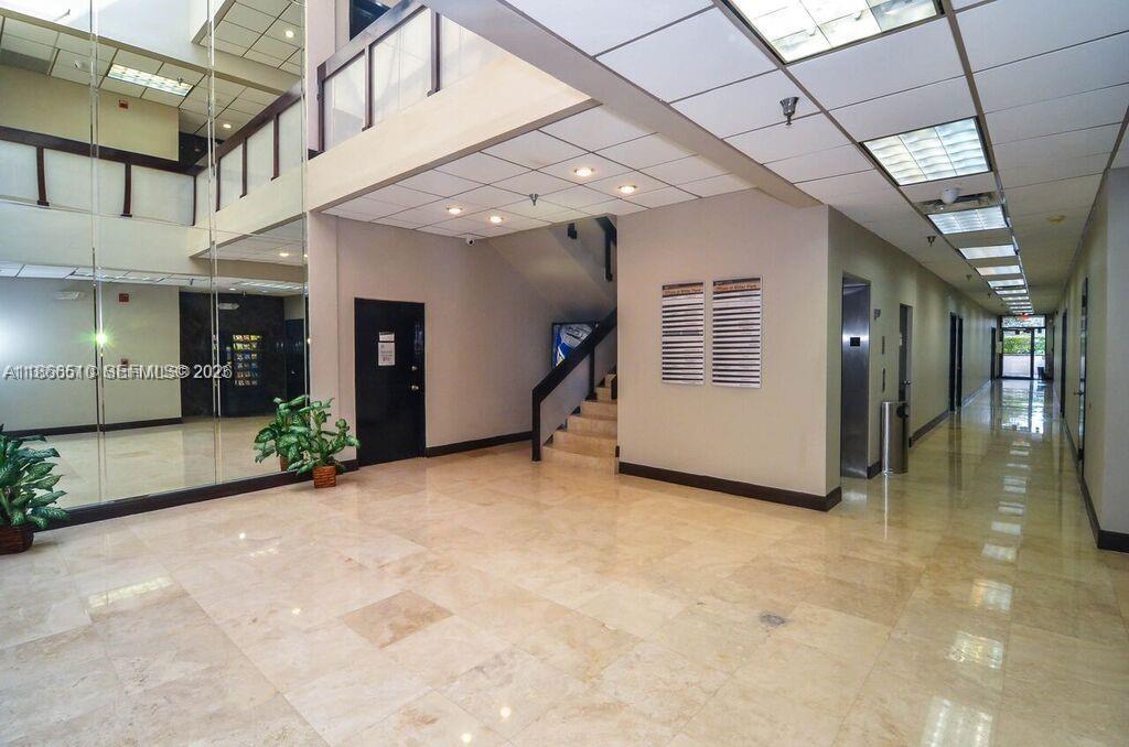 A bright, tiled lobby features a staircase, a long hallway, and mirrored walls — 5600 SW 135th Ave, Miami FL 33183, MIAMI, FL