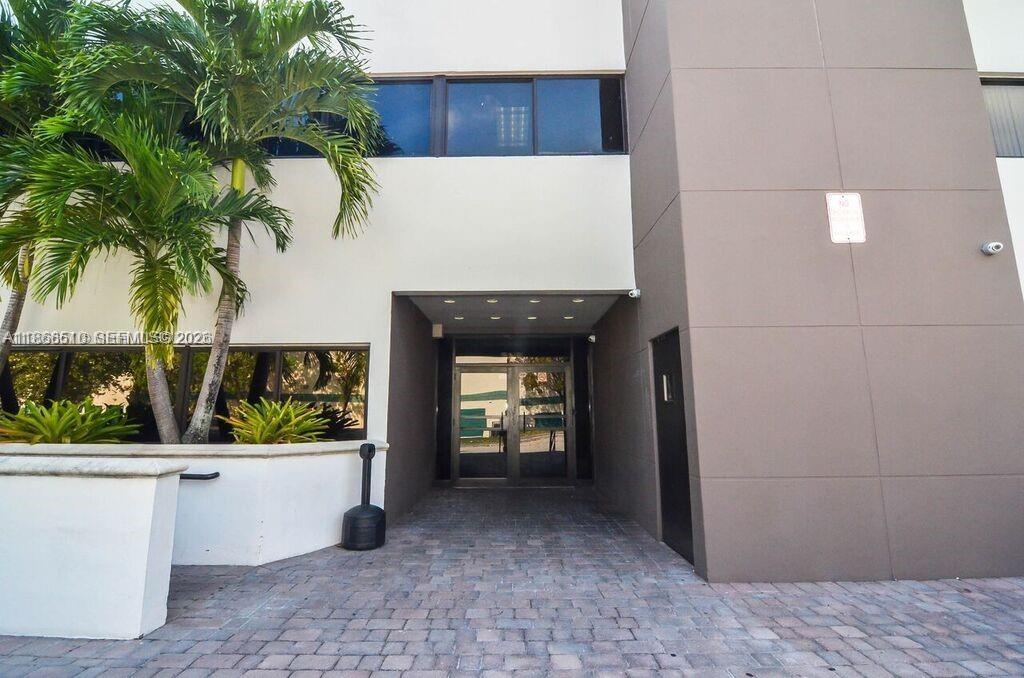 A paved walkway leads to the glass-paned entrance of a modern building with palm trees — 5600 SW 135th Ave, Miami FL 33183, MIAMI, FL