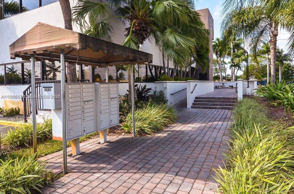 An outdoor mail kiosk stands on a paved walkway near building stairs and palm trees — 5600 SW 135th Ave, Miami FL 33183, MIAMI, FL