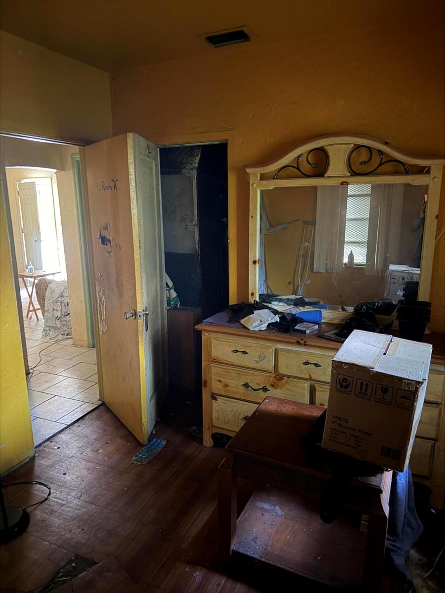 A bedroom features a wooden dresser with a mirror, yellow walls, and an open doorway — 1280 NW 51ST Street, Miami FL 33142, MIAMI, FL