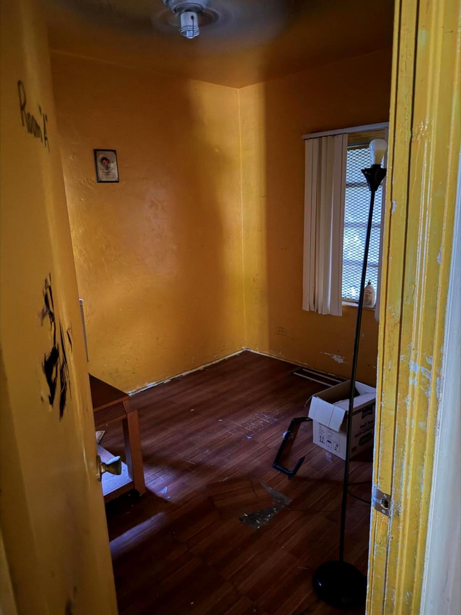 A small, empty room with yellow walls, wood-look flooring, and a window with vertical blinds — 1280 NW 51ST Street, Miami FL 33142, MIAMI, FL