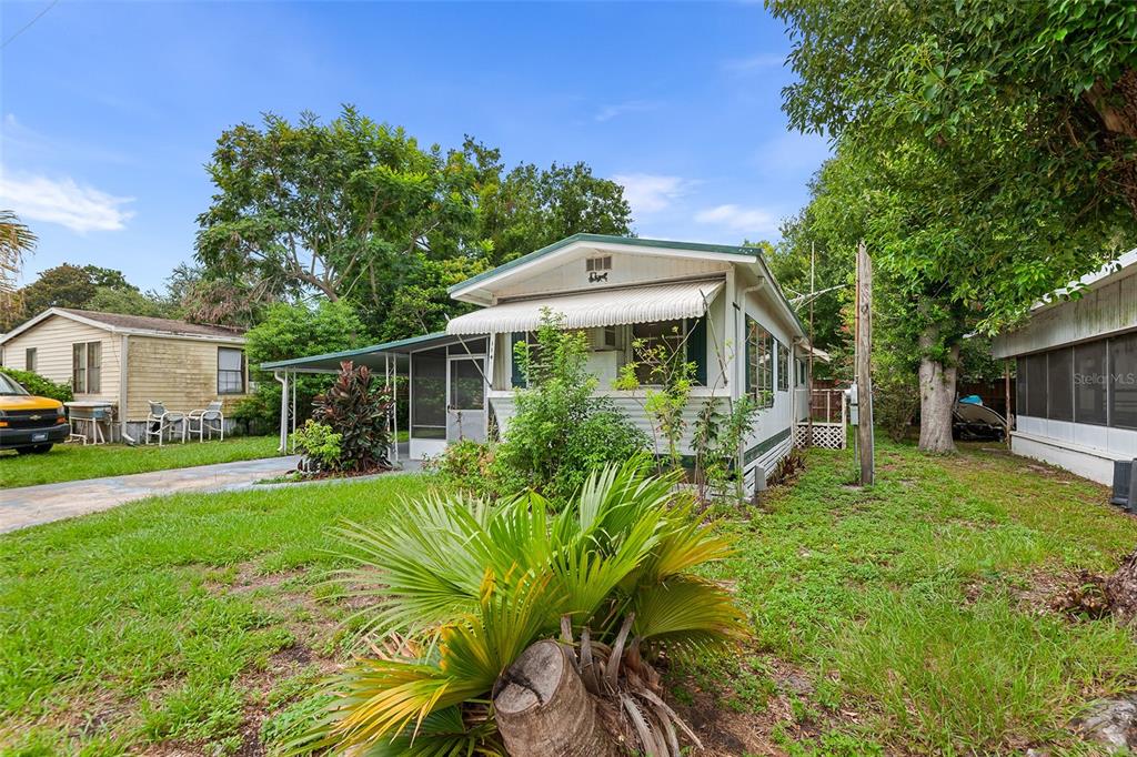 A single-story mobile home with a white exterior, metal awning, and a screened-in porch — 114 LAKESIDE DR, AUBURNDALE, FL