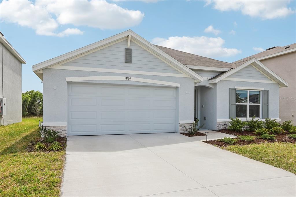 A light blue single-story house features a two-car garage and a concrete driveway — 1804 TAHITIAN SUNRISE DRIVE, PLANT CITY, FL