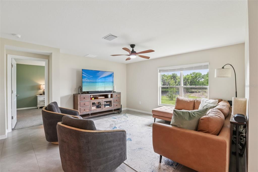 A living room features a brown leather sectional, two gray armchairs, and a television console — 1804 TAHITIAN SUNRISE DRIVE, PLANT CITY, FL
