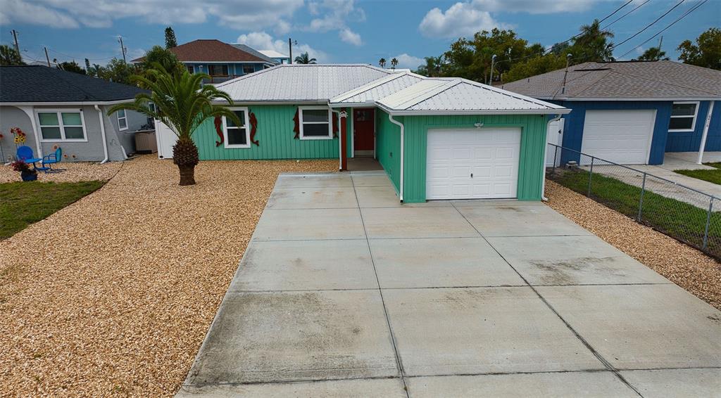 A teal single-story house with a white metal roof and a concrete driveway — 6420 BOATYARD DRIVE, HUDSON, FL