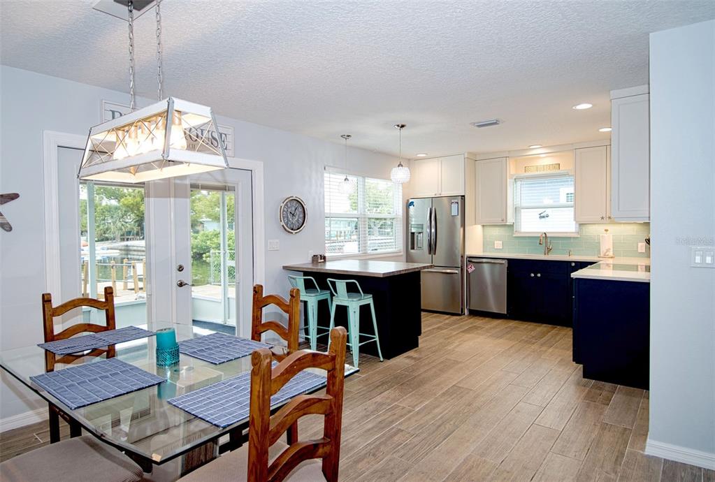 A kitchen and dining area feature dark blue cabinets, stainless steel appliances, and wood-look flooring — 6420 BOATYARD DRIVE, HUDSON, FL