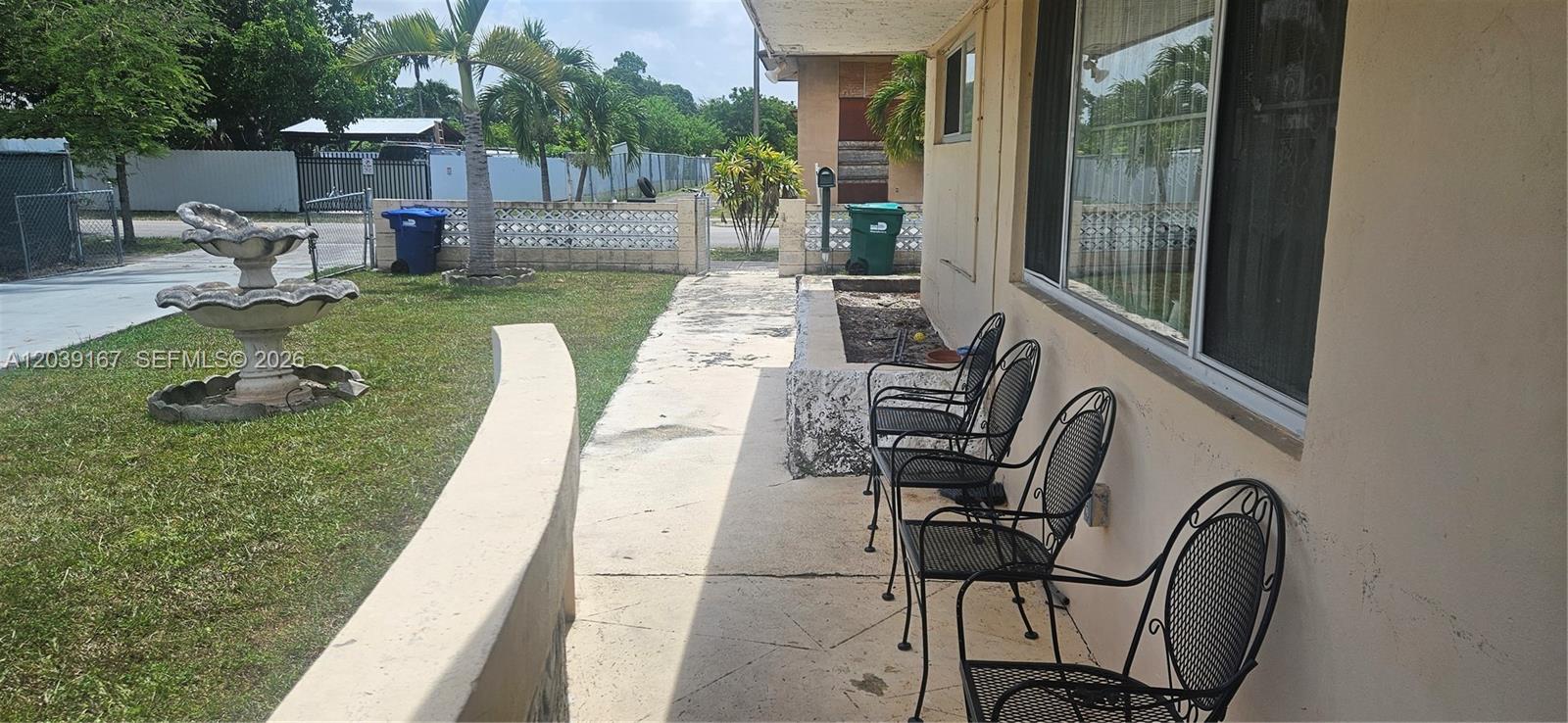 A concrete patio features three black metal chairs next to a house with a fountain — 5955 NW 18th Ave, Miami FL 33142, MIAMI, FL