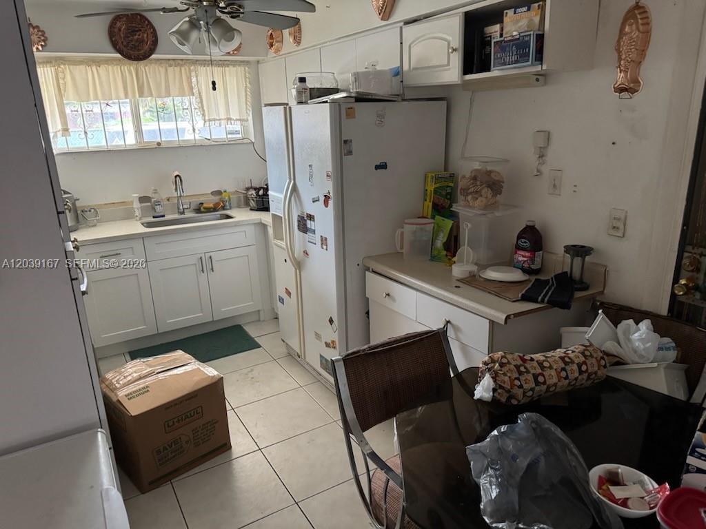 A kitchen with white cabinets, a white refrigerator, and a dining table in the foreground — 5955 NW 18th Ave, Miami FL 33142, MIAMI, FL