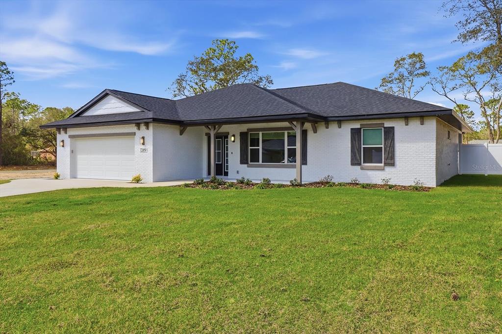 A single-story white brick house with a dark roof and a two-car garage — 7289 N WESTBROOK WAY, CITRUS SPRINGS, FL