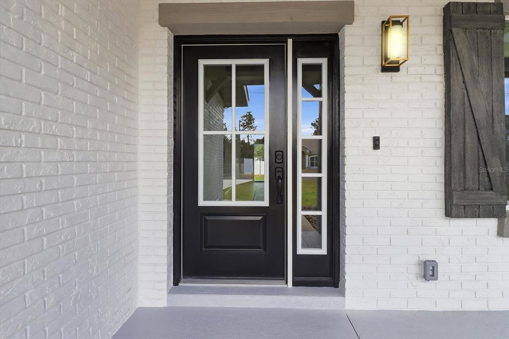 A black front door with glass panels is set into a white painted brick wall — 7289 N WESTBROOK WAY, CITRUS SPRINGS, FL