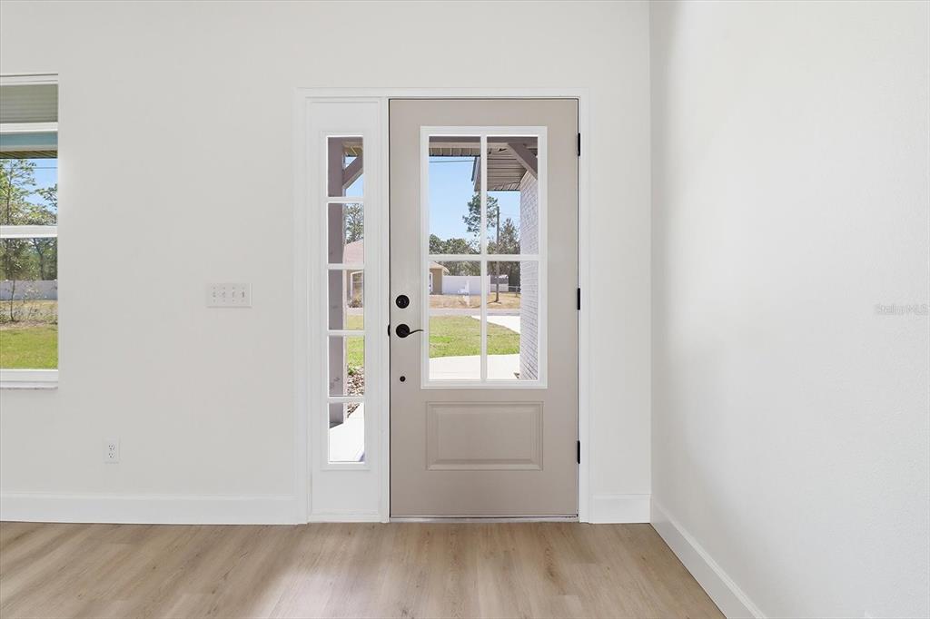 A light-colored front door with a glass panel and sidelight sits in a white room — 7289 N WESTBROOK WAY, CITRUS SPRINGS, FL