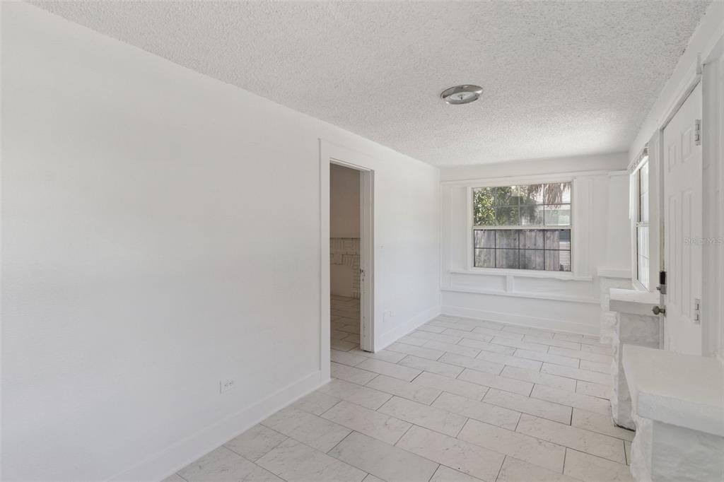 A bright, empty room with white walls, tile flooring, a window, and a doorway — 1743 YALE STREET S, ST PETERSBURG, FL
