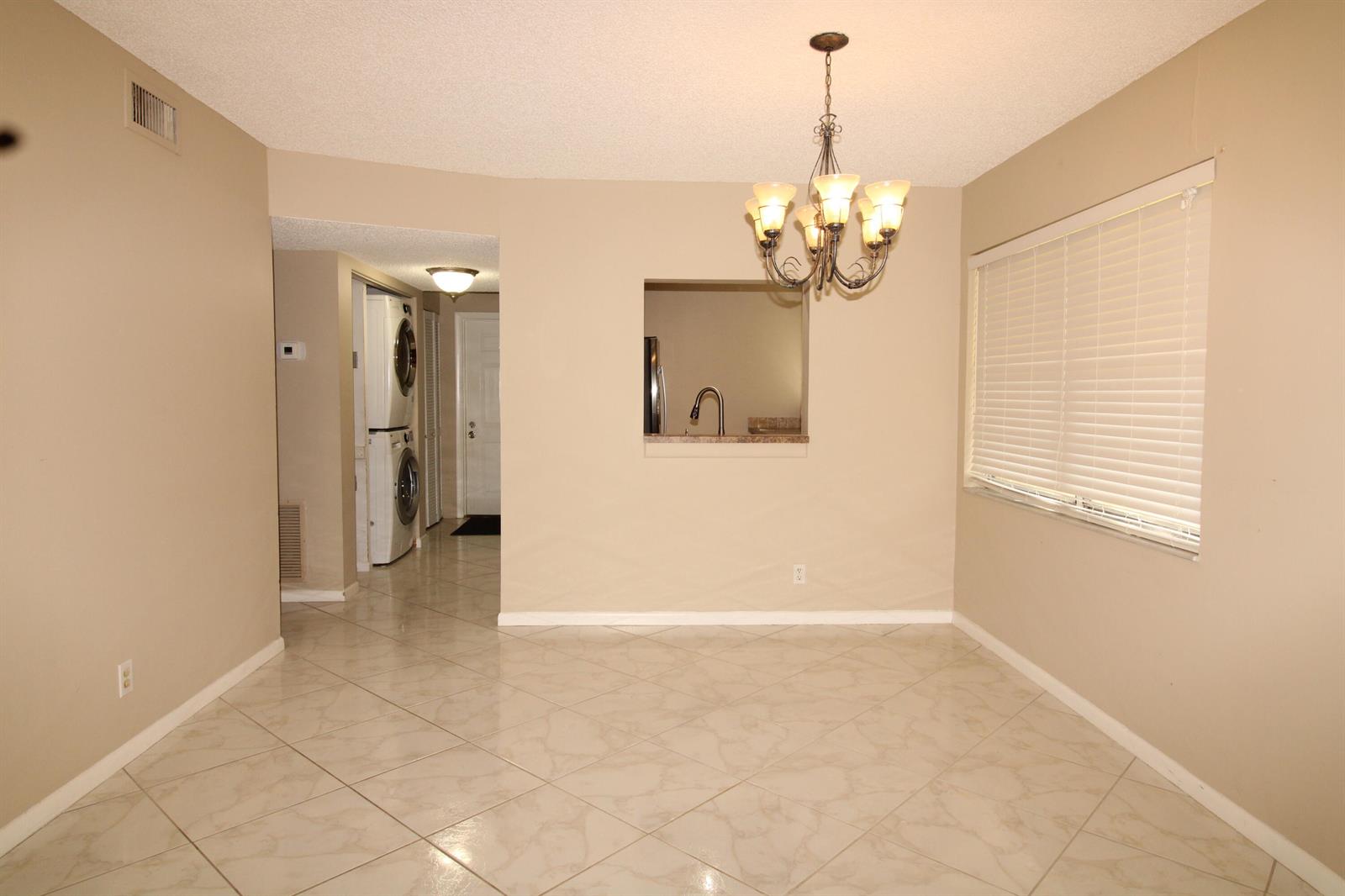 A dining area with beige walls, tile flooring, a chandelier, and a kitchen pass-through window — 2955 SW 22nd Avenue # 2080, Delray Beach FL 33445, DELRAY BEACH, FL