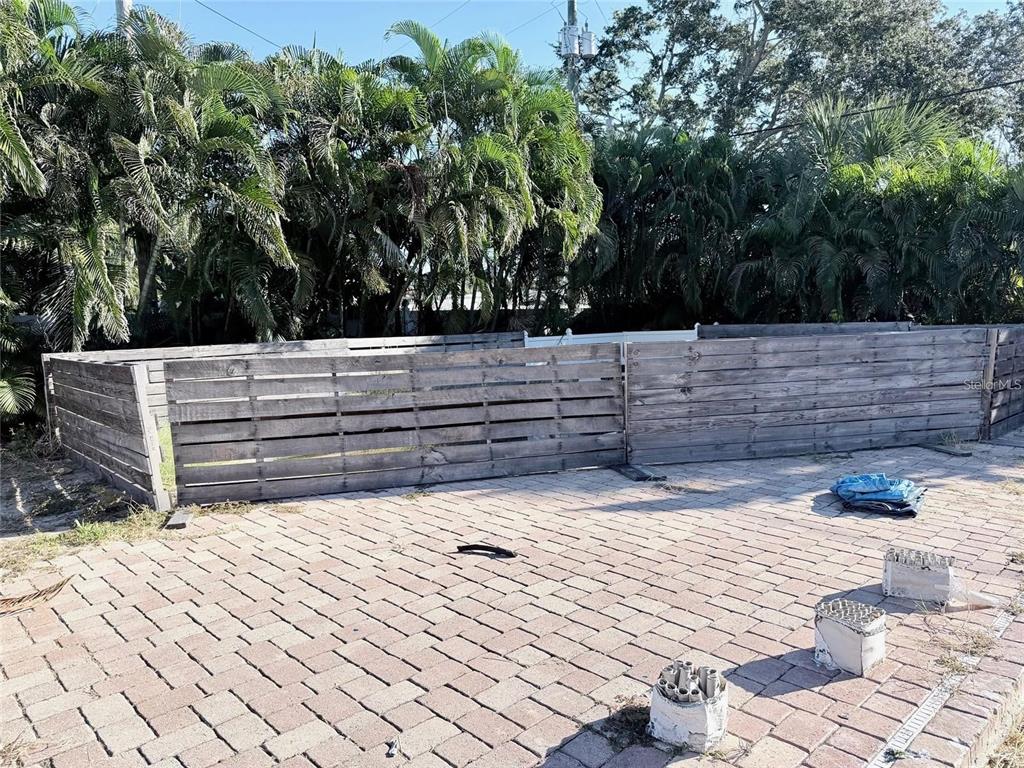 A wooden fence encloses a paved patio area with palm trees in the background — 3626 S OMAR AVENUE, TAMPA, FL