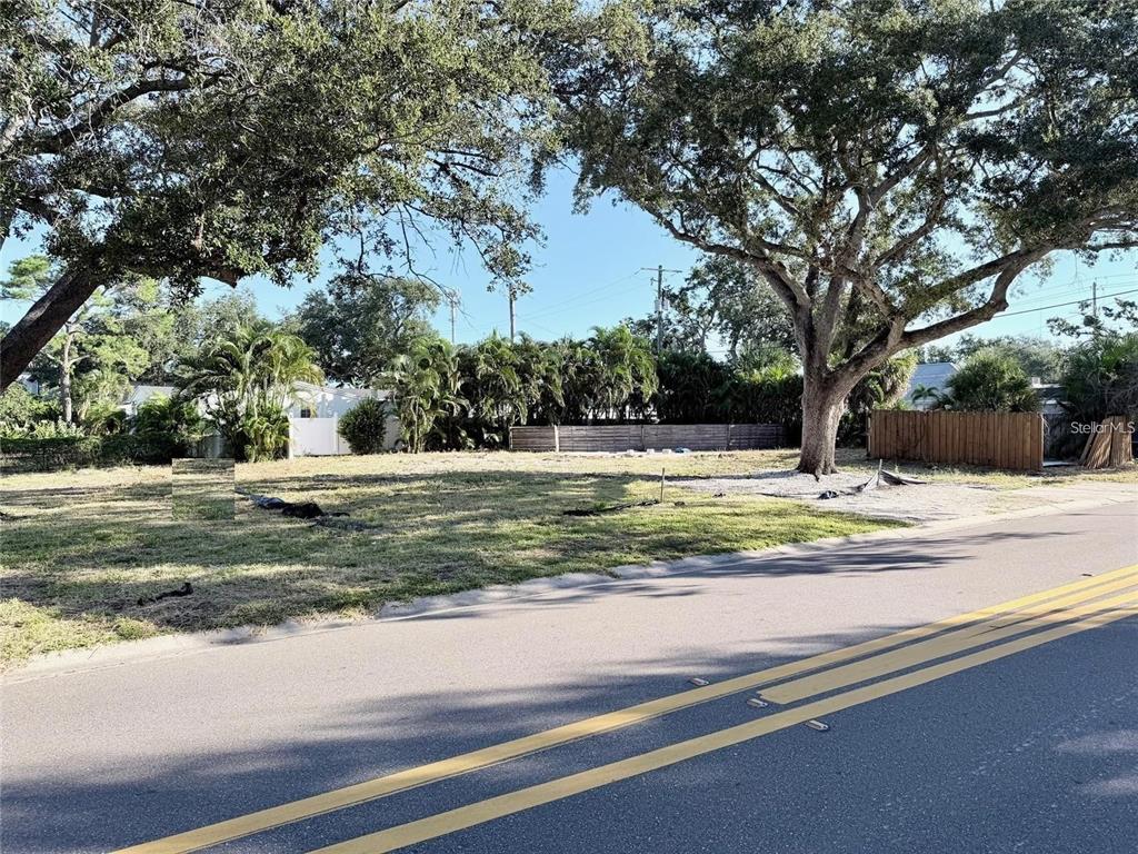 A vacant, grassy residential lot features several large mature trees and a wooden fence — 3626 S OMAR AVENUE, TAMPA, FL