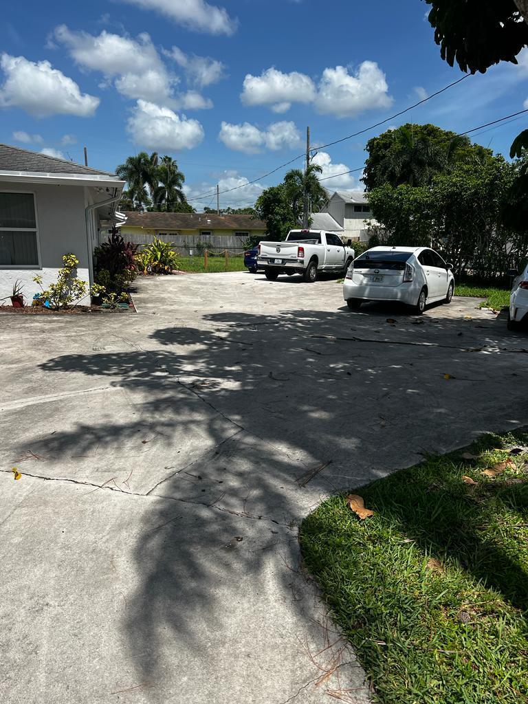 A concrete driveway leads to a house with a white pickup truck and a white car — 4429 Melvin Road # A, FL 33461, FL
