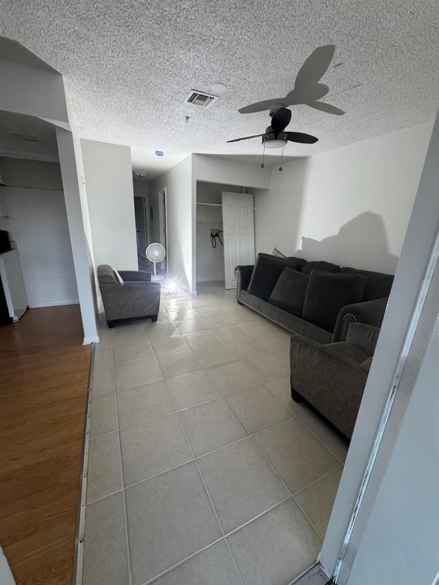 A living room with tile flooring, a dark sofa, an armchair, and a ceiling fan — 4429 Melvin Road # A, FL 33461, FL