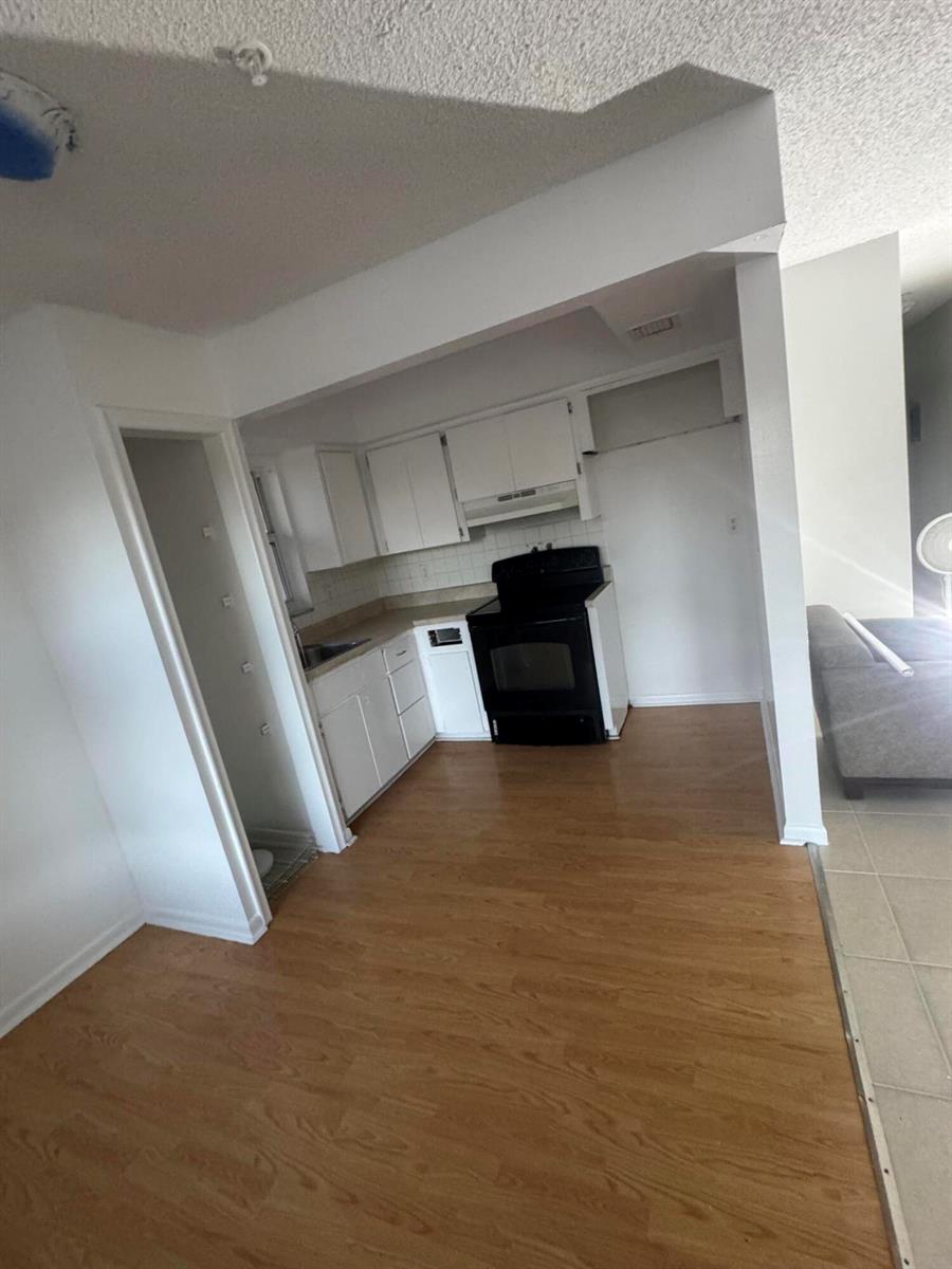 A kitchen with white cabinets, a black stove, and light wood-look flooring — 4429 Melvin Road # A, FL 33461, FL