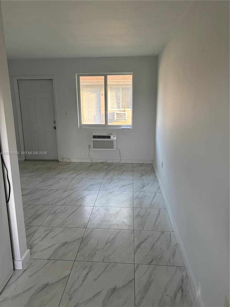 A room with white walls, light marble-patterned tile flooring, a window, and a wall-mounted air conditioner — 14399 NE 5th Pl # 3, North Miami FL 33161, NORTH MIAMI, FL