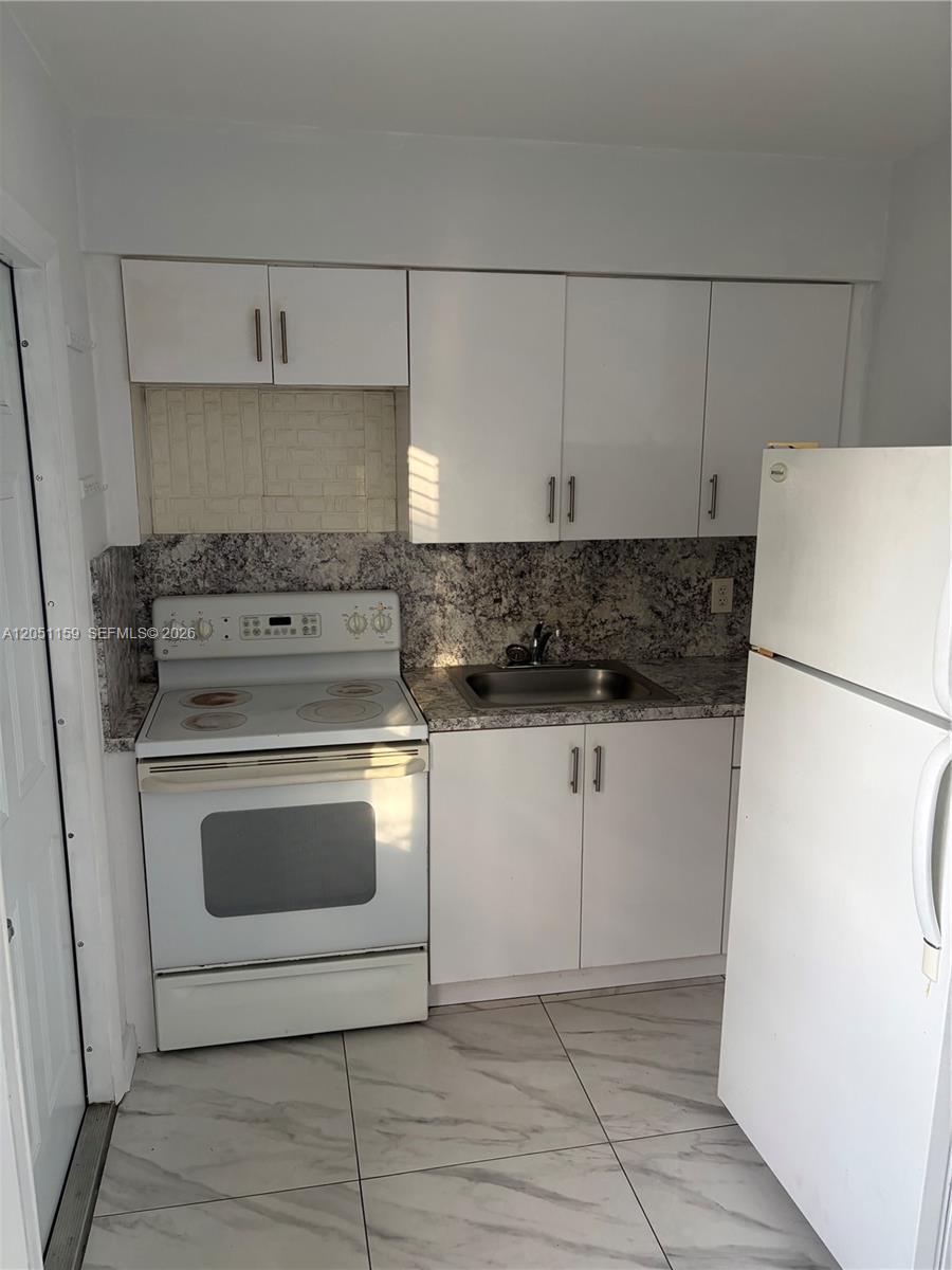 A small kitchen features white cabinets, a white electric stove, a sink, and granite countertops — 14399 NE 5th Pl # 3, North Miami FL 33161, NORTH MIAMI, FL