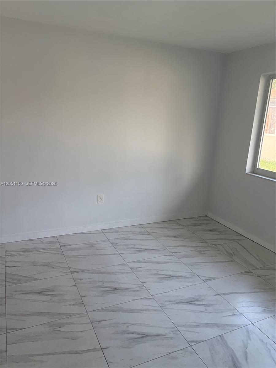 An empty room features light gray walls, white baseboards, and white marble-patterned tile flooring — 14399 NE 5th Pl # 3, North Miami FL 33161, NORTH MIAMI, FL