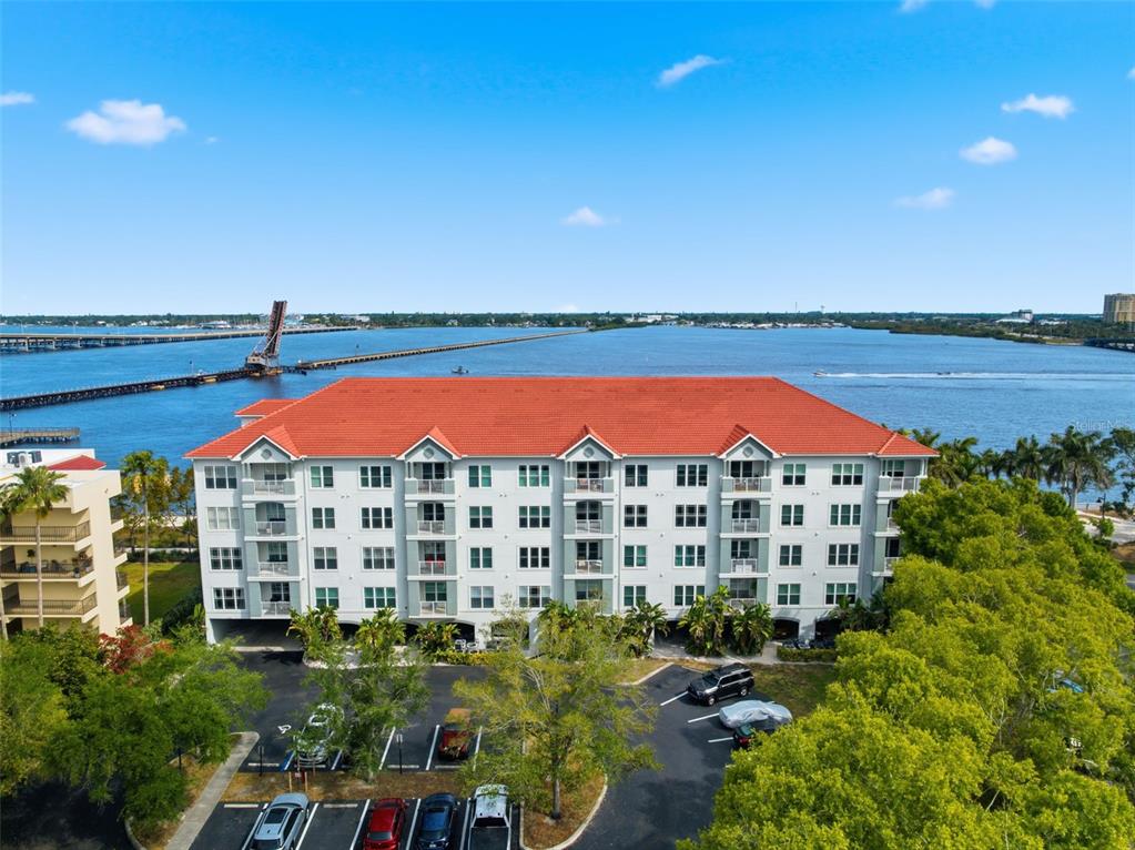 An aerial view of a multi-story apartment building with a red roof near water — 210 3RD STREET W UNIT 8305, BRADENTON, FL