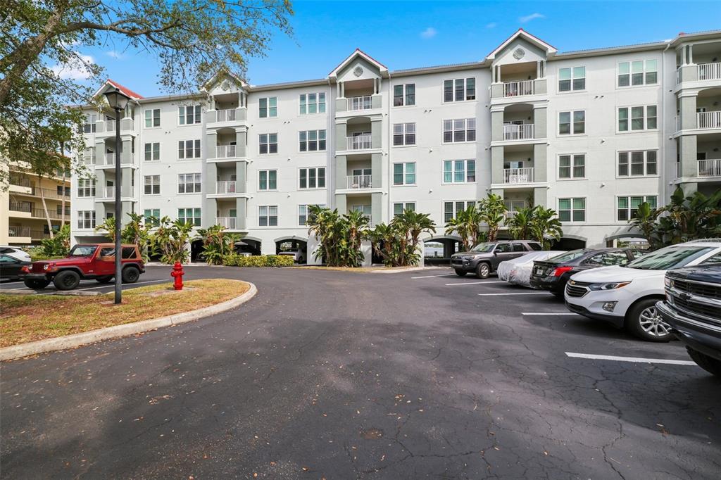 A multi-story apartment building with a parking lot and several parked cars in front — 210 3RD STREET W UNIT 8305, BRADENTON, FL