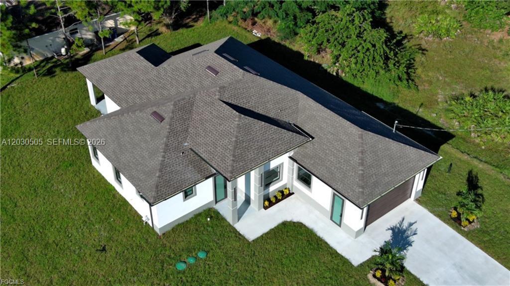 An aerial view shows a single-story house with a shingled roof and a concrete driveway — 3512 9TH STREET W, Lehigh Acres FL 33971, LEHIGH ACRES, FL