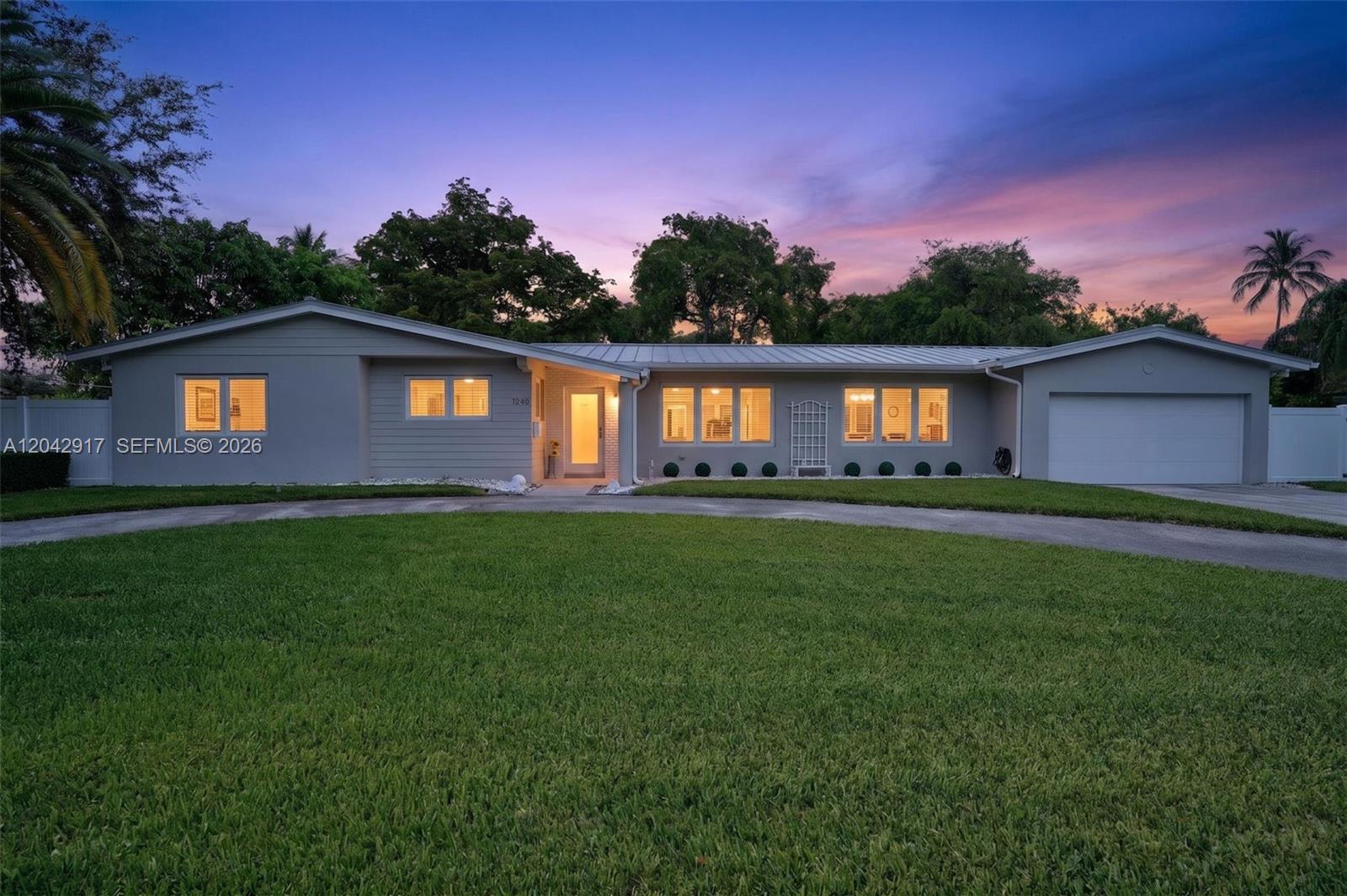 A single-story gray house with a metal roof and a large front lawn at dusk — 7240 SW 131st St, Pinecrest FL 33156, PINECREST, FL