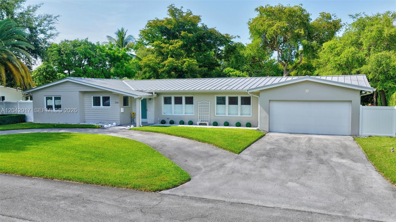 A single-story house with a light-colored exterior, metal roof, and a paved driveway — 7240 SW 131st St, Pinecrest FL 33156, PINECREST, FL